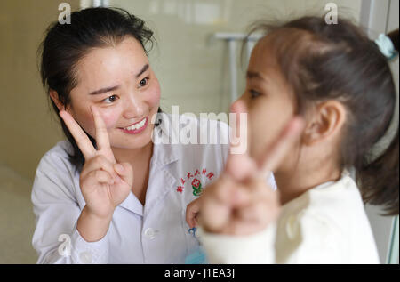 (170421) -- URUMQI, 21 aprile 2017 (Xinhua) -- terapista della riabilitazione Cao Beibei (L) incoraggia una delle figlie gemelle durante la riabilitazione di formazione presso le sei affiliato ospedale di Xinjiang Medical University in Urumqi, capitale del nord-ovest della Cina di Xinjiang Uygur Regione autonoma, 17 aprile 2017. Il sei-anno-vecchio gemelli da Uzbekistan diagnosticati di paralisi cerebrale, quando sono venuto in Cina nel novembre 2016, entrambi di essi non è in grado di camminare in modo indipendente ed esprimere chiaramente. Dopo essere stata trattata con agopuntura, massaggi terapeutici, la medicina di erbe e terapia di riabilitazione, i gemelli poteva camminare inde Foto Stock