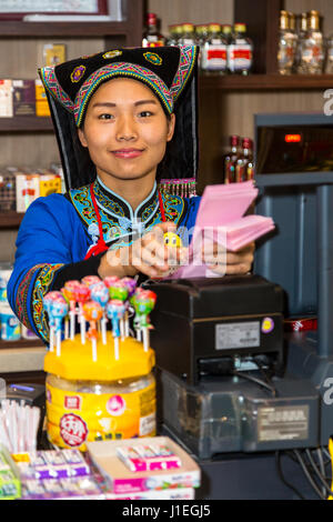 Guizhou, Cina. Han giovane donna cinese in abito Bouyei, lavorando in una banchina di riposo. Foto Stock