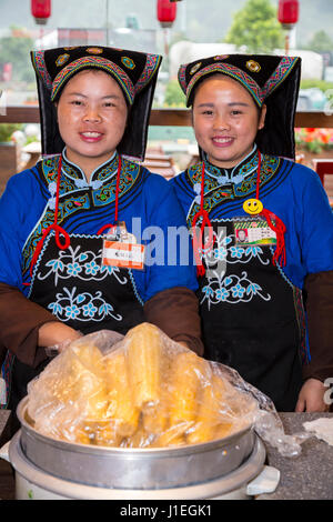 Guizhou, Cina. I giovani Han le donne cinesi in abito Bouyei, lavorando in una banchina di riposo. Foto Stock