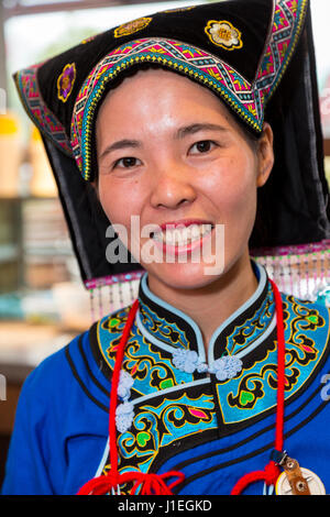 Guizhou, Cina. Han giovane donna cinese in abito Bouyei, lavorando in una banchina di riposo. Foto Stock