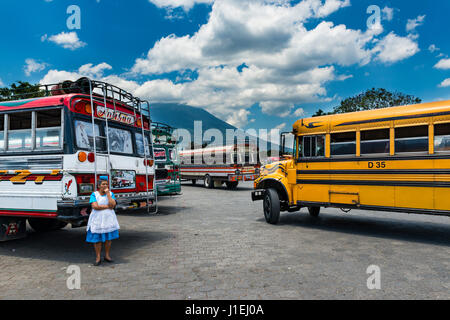 Antigua Guatemala - Aprile 19, 2014: Donna in un bus terminal con autobus colorati in Antigua, Guatemala Foto Stock