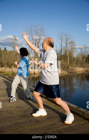 Un colpo di un senior asian giovane praticante taichi esercizio Foto Stock