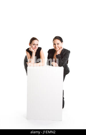 Un isolato colpo di due imprenditrici con un cartellone vuoto Foto Stock
