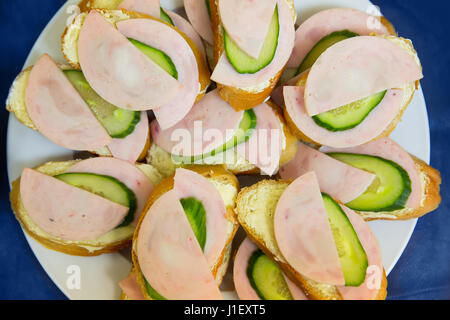 Panino con salsiccia e il cetriolo sul tavolo blu Foto Stock