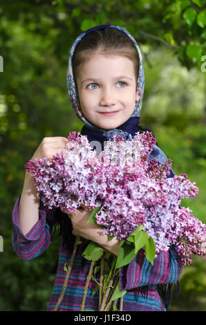 Bellissima bambina con un bouquet di una fioritura lilla in mano Foto Stock