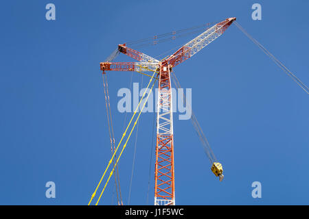 Grosso boom di gru cingolate (rosso e bianco) con cielo blu sullo sfondo. Foto Stock