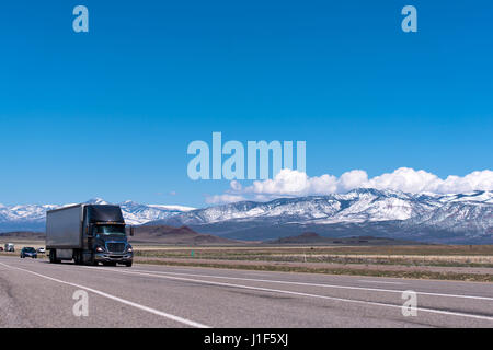 Nero elegante moderno big rig semi carrello con semi rimorchio sulla superstrada passa montagne nella neve Foto Stock