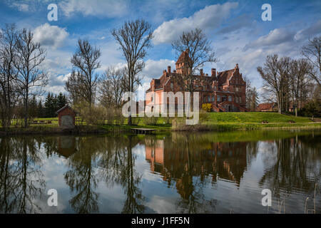 Jaunmoku castello vicino Tukums, Lettonia riflettente nel lago. Splendido cielo blu e nuvole scenico in background in una giornata di sole. Vista da cartolina. Foto Stock