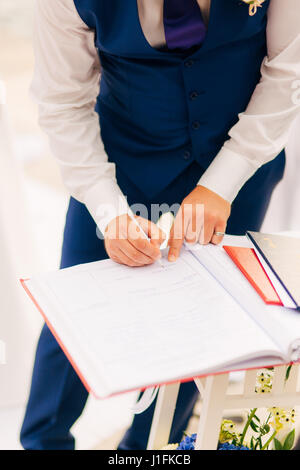 Sposi mettere le loro firme nell'atto di registrazione di un matrimonio Foto Stock