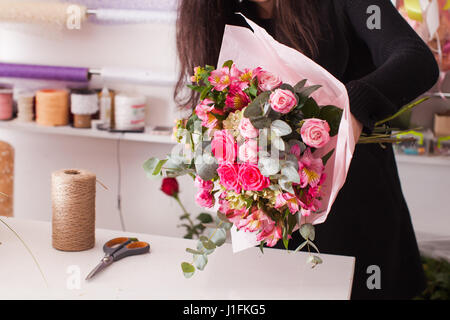 Fioraio rendendo il bouquet con rose Foto Stock