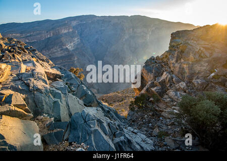 Jebel Shams; sole risplende nel corso del vertice e gorge in Oman il Grand Canyon Foto Stock