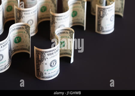 Pochi un dollaro banconote curva come segno su sfondo scuro Foto Stock