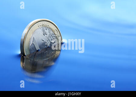 Crisi economia concetto. Primo piano di una moneta in euro che affonda in acqua Foto Stock