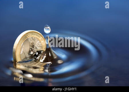 Primo piano di una moneta in euro che affonda in acqua con splash Foto Stock