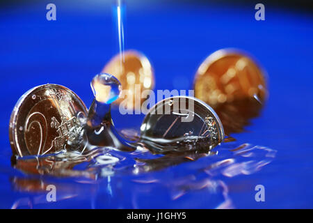 Primo piano di alcune monete in euro che affonda in acqua con splash Foto Stock