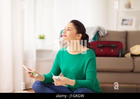 Donna felice con il denaro e la borsa da viaggio a casa Foto Stock