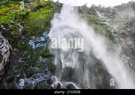 Bagnare al di sotto di una cascata nel Milford Sound, uno dei fiordi più belli in Nuova Zelanda Foto Stock