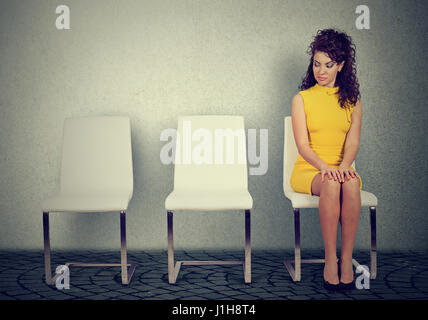 Giovane donna seduta su una sedia in attesa per il colloquio di lavoro Foto Stock