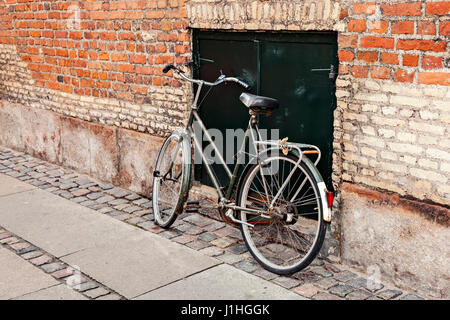 Vintage bicicletta appoggiata contro il vecchio muro di mattoni. Foto Stock
