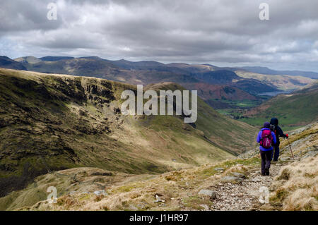 Maschio e femmina escursionisti discendente dalla High Street in pascoli fondo verso Hartsop, Patterdale e Ullswater nel distretto del Lago Foto Stock