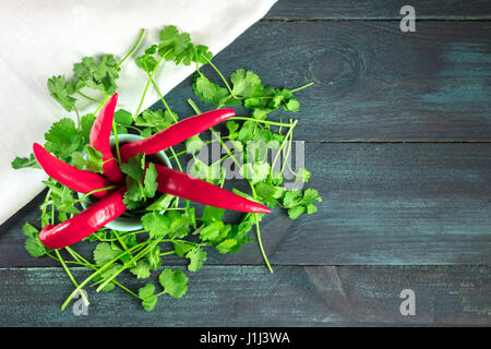Una foto aerea di peperoncino rosso, verde foglie di coriandolo, e un panno bianco, che rappresentano i colori della bandiera messicana, al buio su un texture con Foto Stock