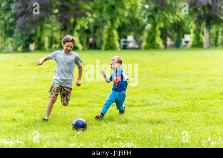 Vista giorno di due ragazzi che giocano a calcio d'estate il parco. Foto Stock