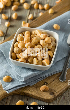 Noci di macadamia, in ciotole bianche. Frutta secca con guscio di