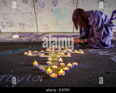 Chanhassen, Minnesota, Stati Uniti d'America. Xxi Aprile, 2017. Una donna accende una candela in un monumento al principe nel tunnel pedonale di fronte a Paisley Park, la sua ex casa e studio di registrazione. Il tunnel è diventato un memoriale al principe, persone hanno attirato graffiti nel tunnel in onore di lui e lasciano memoriali nel tunnel. La superstar è morto da un sovradosaggio accidentale del fentanil oppioidi il 21 aprile 2016. Venerdì è stato il primo anniversario della sua morte. Una folla di persone raccolte a Paisley Park, che è ora un museo in onore del Minnesota nato musicista. (Credito Immagine: © Jack Kurtz via ZUMA Wi Foto Stock