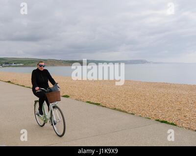 Weymouth Dorset, Regno Unito. 22 apr, 2017. Una donna di cicli lungo la passeggiata su un nuvoloso ma luminosa giornata con una temperatura di 13°C. © DTNews/Alamy Live Credito: Dan Tucker/Alamy Live News Foto Stock