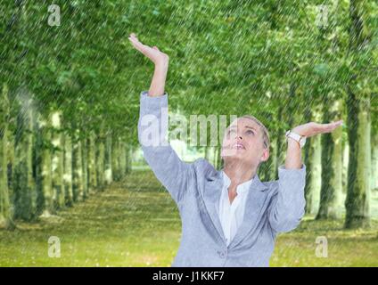 Composito Digitale di Business donna sotto la pioggia nel parco Foto Stock