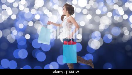Composito Digitale della donna azienda borse per lo shopping passeggiando contro bokeh di fondo Foto Stock