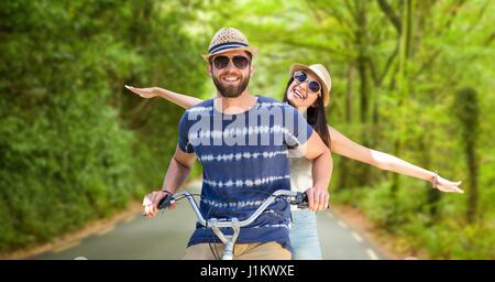 Composito Digitale di coppia felice equitazione bicicletta su strada Foto Stock