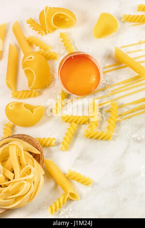 Vari tipi di pasta su marmo bianco con la farina e un uovo, formando una cornice per il testo Foto Stock