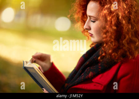 Profilo di zenzero lettura femminile al di fuori del libro Foto Stock