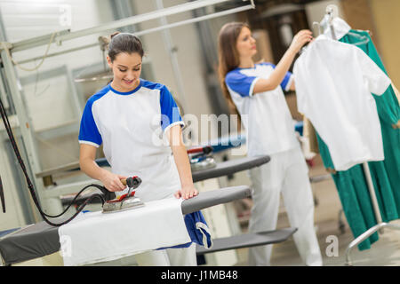 Soddisfatto dei lavoratori tessili di stiratura sulla tavola da stiro Foto Stock