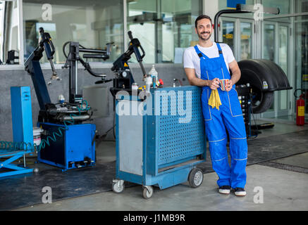 Sorridente ingegnere maschio in un negozio di riparazioni auto Foto Stock