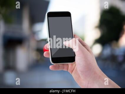 Composito Digitale di mano con telefono contro sfocata street Foto Stock