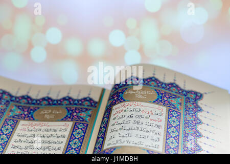 Aprire le pagine del libro sacro Corano con lo sfondo delle luci Foto Stock