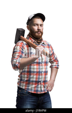 Redhead uomo barbuto che indossa un cappello da baseball e shirt tenendo un martello su una spalla con un'espressione. Foto Stock