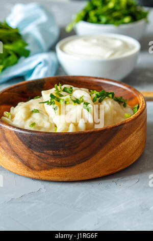 Cucinato europeo orientale gnocchi, vareniki con panna acida con prezzemolo su sfondo grigio. Foto Stock