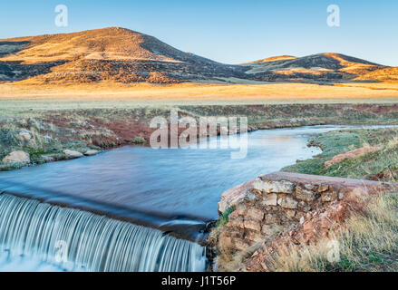 Una piccola diga in Colorado settentrionale pedemontana - Parco Creek è in esecuzione l'acqua deviata dalla forcella del nord del fiume Poudre per riempire un serbatoio downstre Foto Stock