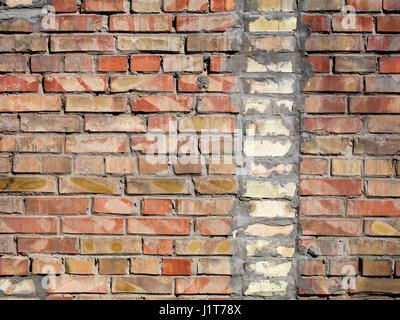 Su un vecchio muro di mattoni rossi separati un frammento verticale del vecchio mattone di silicato Foto Stock