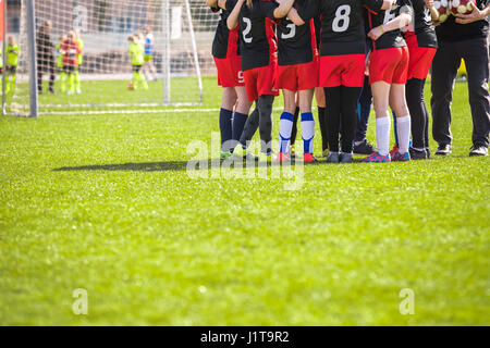 I bambini della squadra di calcio del passo. Ragazze in bianco e nero e rosso kit calcio insieme permanente sul campo di calcio. Giovani motivati i giocatori di calcio con Foto Stock