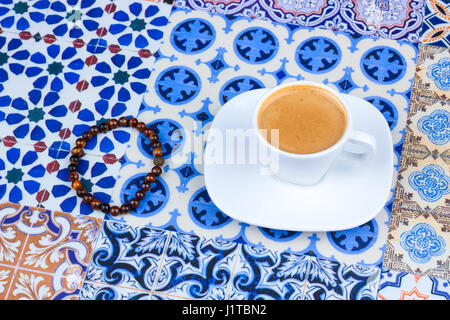 Tazza di caffè arabico su un Orientale sfondo colorato / tazza di espresso su una orientale colorato con fiori, anelli e Tamr date Foto Stock