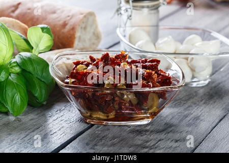 Ingredienti pronti per preparare la bruschetta con pomodori secchi e olive e formaggio. Cucina italiana Foto Stock
