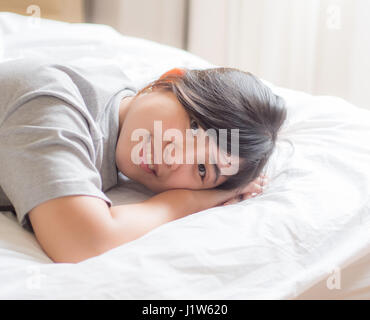Donna cinese giacente sul letto Foto Stock