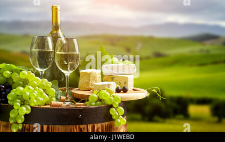 Vino bianco bottiglia e bicchiere di vino in botte barile. Bella Toscana sullo sfondo Foto Stock