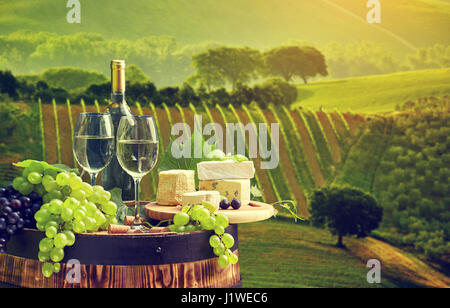 Vino bianco bottiglia e bicchiere di vino in botte barile. Bella Toscana sullo sfondo Foto Stock