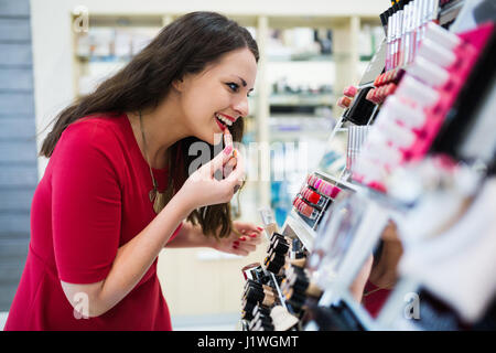 Bella bruna donna test rossetti al negozio di cosmetici Foto Stock