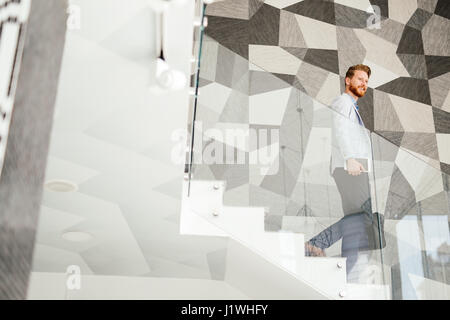 Imprenditore in suite ritratto su scale in edificio per uffici Foto Stock